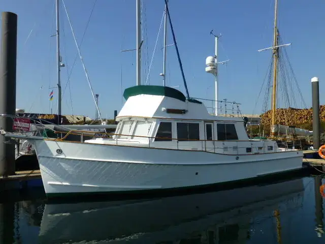 Grand Banks 42: white hull and wheelhouse with flybridge and mast, moored in a marina on a sunny day
