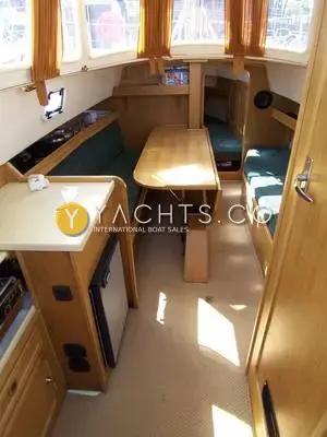 Haber 800: saloon in light oak with green upholstery, folding table and galley sink, looking forward