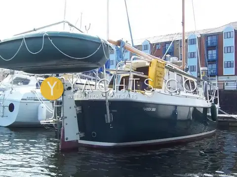 Haber 800: stern quarter with dinghy on stainless davits and dark green hull in marina