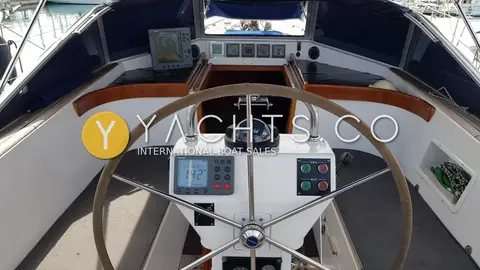 Hallberg-Rassy 43: centre cockpit wheel with autopilot display, furling switches, compass and instrument panel beyond