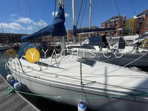 Hanse 301: starboard side view alongside a pontoon with blue sprayhood, mainsail cover and fenders out