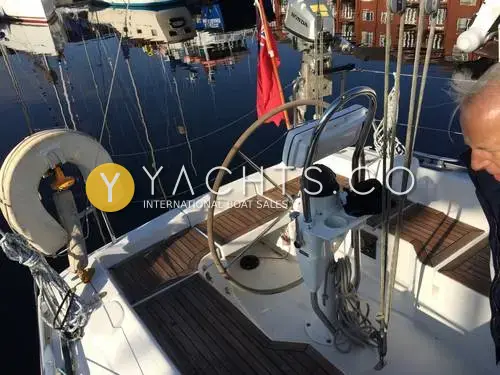 Hanse 315: wheel steering and teak-laid cockpit seats, with red ensign and outboard on the stern bracket