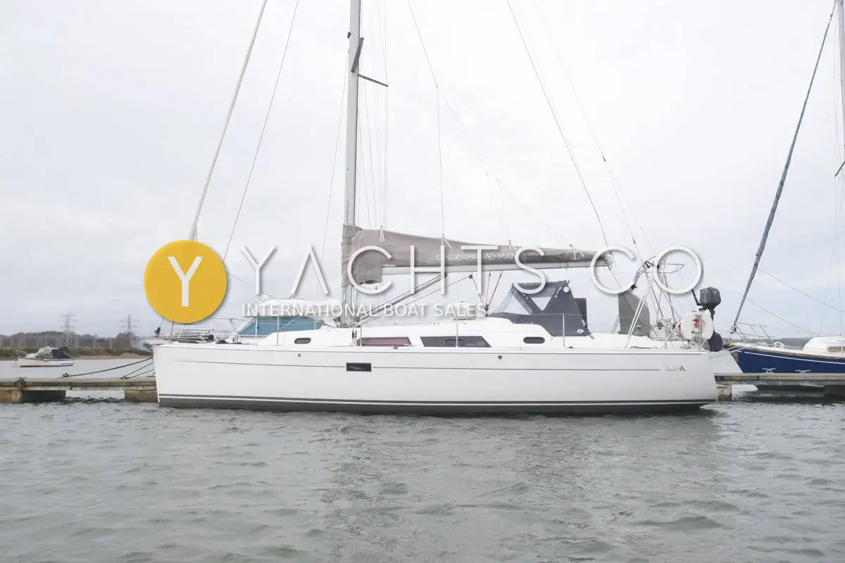 Hanse 370: white hull afloat at a pontoon with sprayhood fitted and mainsail stowed on the boom