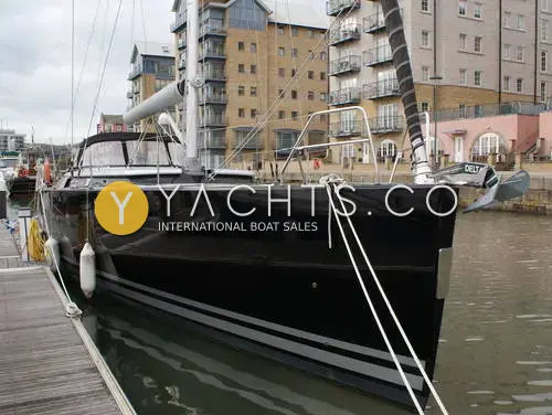 Hanse 545: black hull bow with silver stripes and anchor, moored at marina pontoon beside apartment blocks