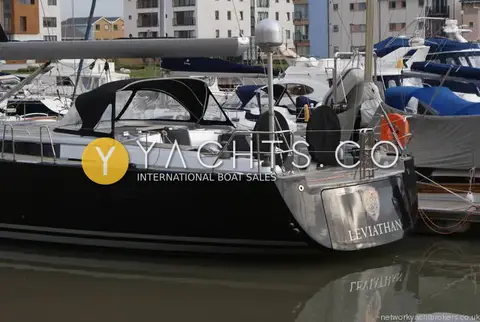 Hanse 545: aft quarter with silver transom and name, black hull and covered wheels in marina