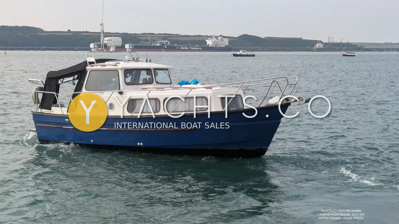Hardy Marine 25: blue-hulled motor boat under way on Milford Haven waterway with tankers moored behind