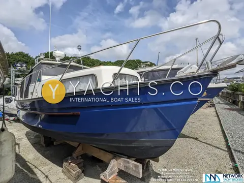 Hardy Marine 25: bow and blue hull shown ashore on wooden blocks with stainless steel bow rail