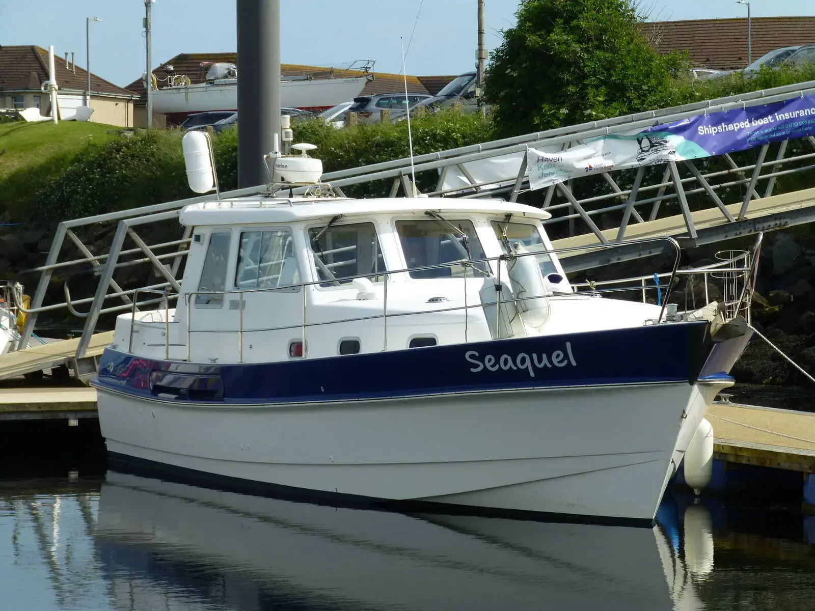 Hardy Marine 32 Commander: starboard bow view of the white and navy hull moored beside a marina gangway