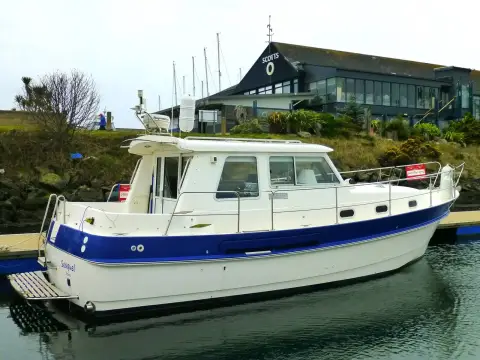 Hardy Marine 32 Commander: port side profile afloat in front of a marina building with dark roof