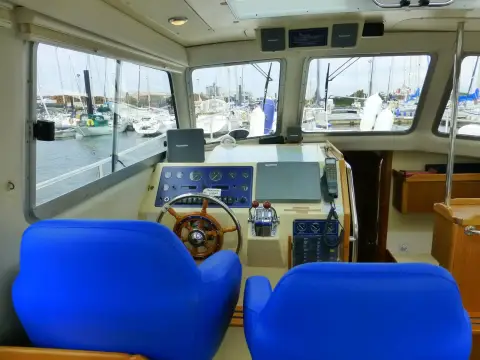 Hardy Marine 32 Commander: twin blue helm seats facing the dashboard and windscreen with marina beyond