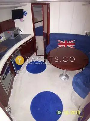 Hardy Marine Seawings 355: saloon with blue curved seating, round wooden table and galley along the port side