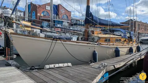 Hillyard 12 Ton: cream carvel hull with fenders out, lying alongside a wooden pontoon