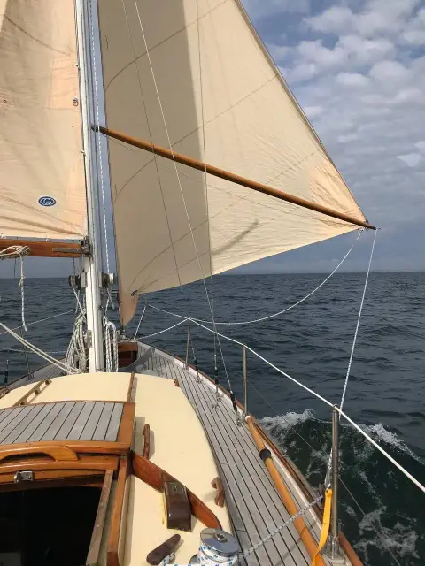 Holman Twister 28: under sail at sea with cream mainsail and headsail and wooden running pole set