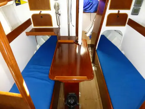 Holman Twister 28: saloon with blue cushioned settees either side of a varnished fixed dining table