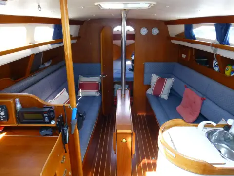 Hunter Channel 323: saloon looking forward with blue settees, central table, galley sink in foreground