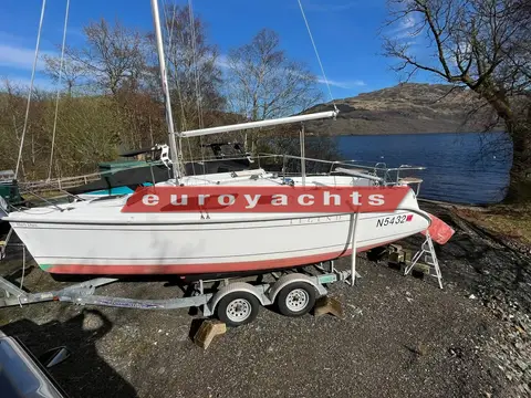 Hunter Legend 25 Trailer Sailer: starboard side on her trailer at a lochside with hills and blue sky behind
