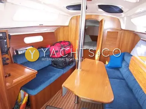 Hunter Legend 326: saloon with blue upholstered settees, varnished drop-leaf table and forward cabin door open
