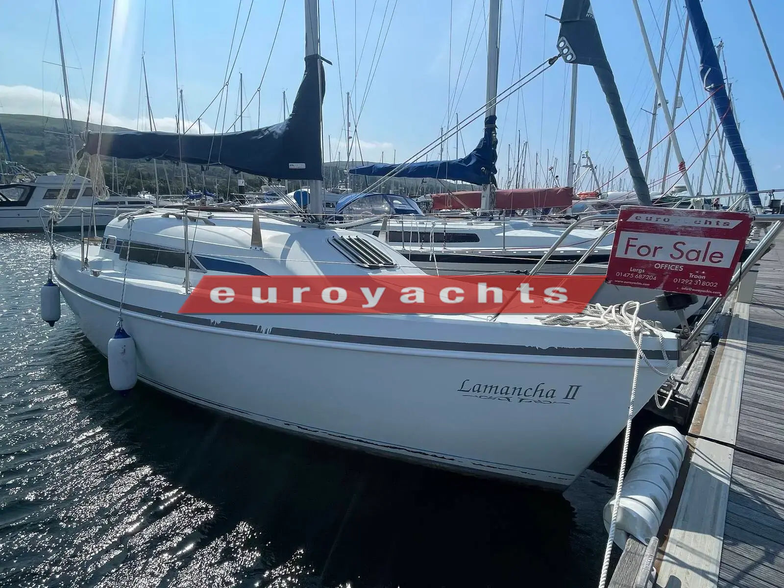 Hunter Ranger 265: white hull from the starboard bow on a pontoon, with blue sail cover and sale sign