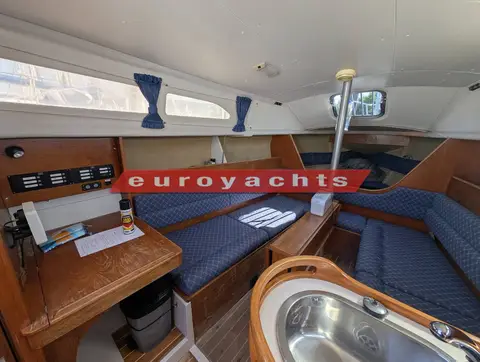 Hunter Ranger 265: saloon with blue upholstered seating, chart table to port and curtained windows