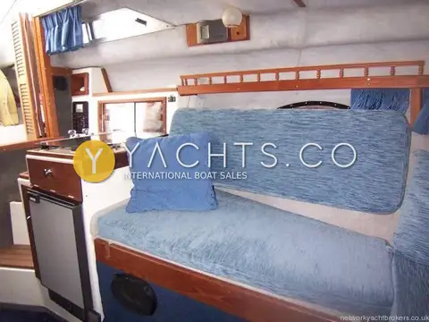 Invader 265: saloon settee in blue upholstery beside the galley unit and fridge