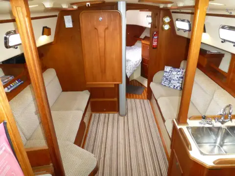 Island Packet 320: saloon looking forward to forward cabin, cream settees either side and galley sink at right