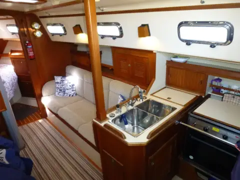 Island Packet 320: saloon and galley with stainless double sink, stove and cream settee along the hull side
