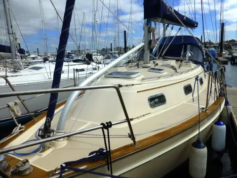 Island Packet 320: side deck with teak toerail, opening portlights, guard wires and fenders over the topsides