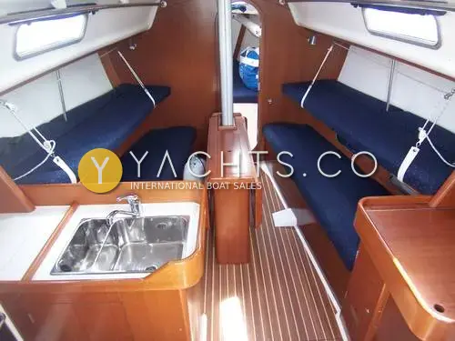 J Boats J/109: saloon looking forward past galley sink, blue upholstered settees with pilot berths above and teak sole