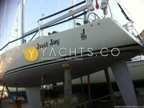 J Boats J/109: hull ashore on stands showing white topsides, dark boot stripes, fin keel and spade rudder