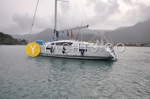 Jeanneau 42 DS: port side at anchor in a calm bay with mountains behind, blue fenders out
