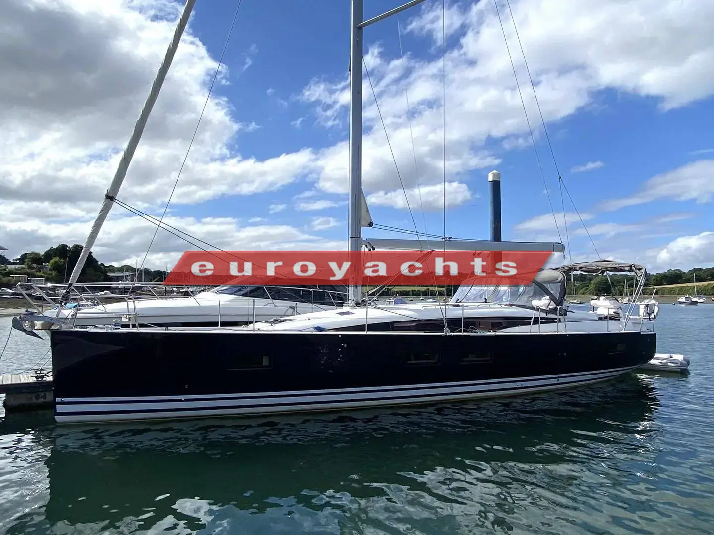 Jeanneau 51: dark blue hull with white boot stripe, berthed at a pontoon on a sunny day