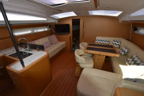 Jeanneau 57: saloon with L-shaped settee, folding table, galley counter and overhead hatches letting in light