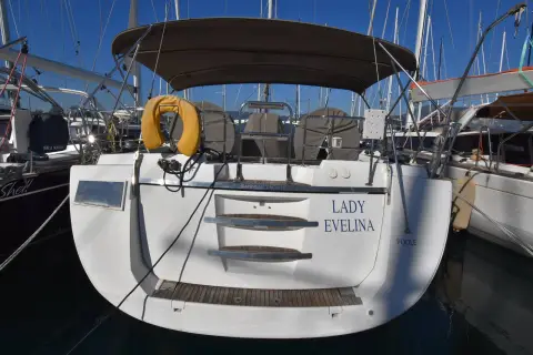 Jeanneau 57: transom with name lettering, swim platform steps and grey bimini, stern-to in marina