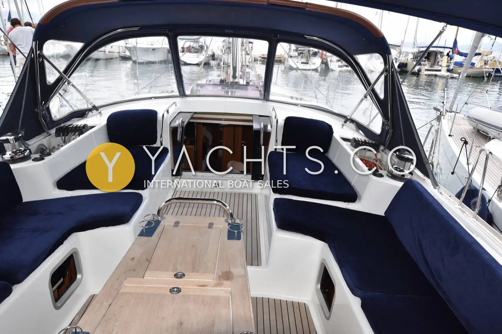 Jeanneau 57 Yacht: cockpit under the sprayhood with navy velour cushions, teak table and open companionway