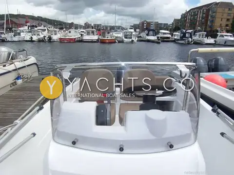 Jeanneau Cap Camarat 4.7C.C: view aft over the windscreen to twin helm seats, wheel and throttle, marina beyond