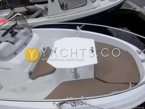 Jeanneau Cap Camarat 4.7C.C: forward cockpit with removable white table and beige cushions around the bow