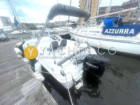 Jeanneau Cap Camarat 5.5 CC: stern view at pontoon showing Bimini top on arch and black Suzuki outboard