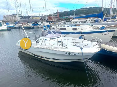 Jeanneau Cap Camarat 5.5 CC: port side of white hull afloat in marina, name on topsides