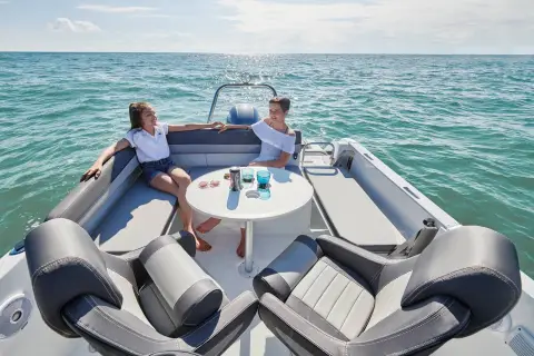 Jeanneau Cap Camarat 6.5 CC: forward cockpit with wrap-around bench seating, central table and two people relaxing