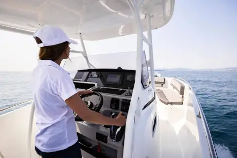 Jeanneau Cap Camarat 7.5 CC: helm station under the T-top with steering wheel, display screen and a woman driving