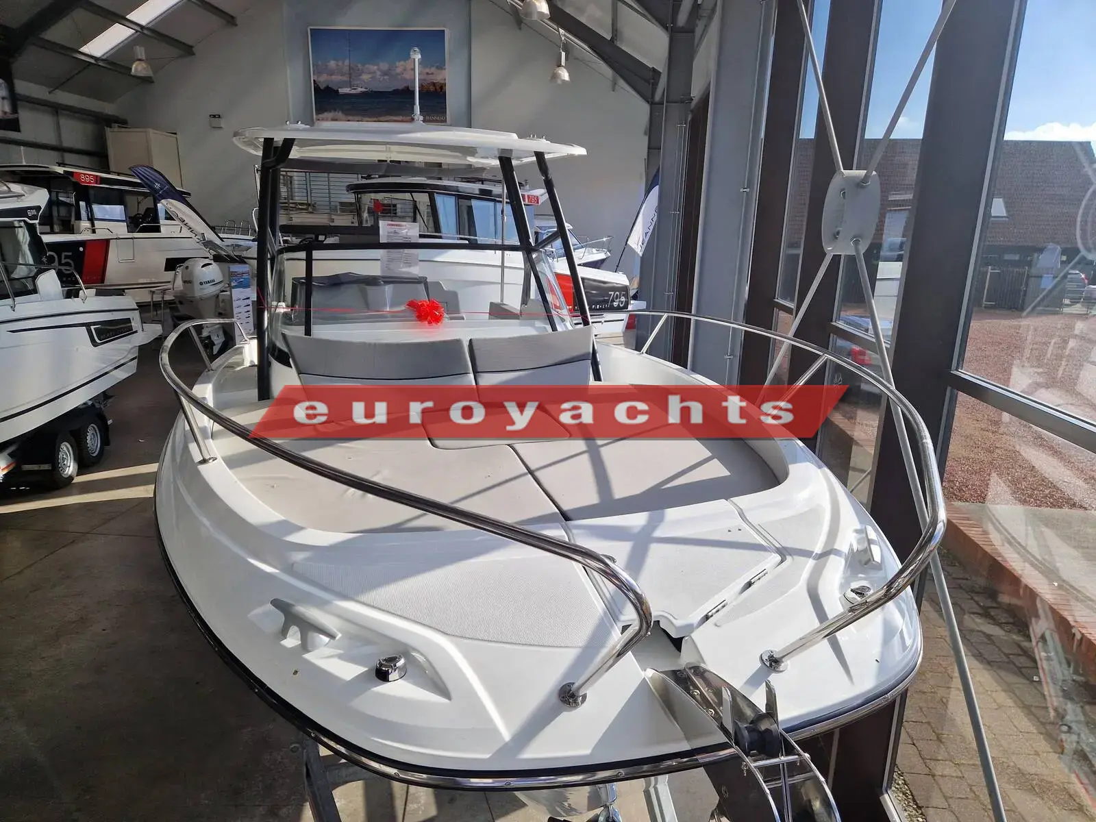 Jeanneau Cap Camarat 7.5 WA S3: bow view in showroom showing foredeck sundeck, pulpit rails and black-framed T-Top