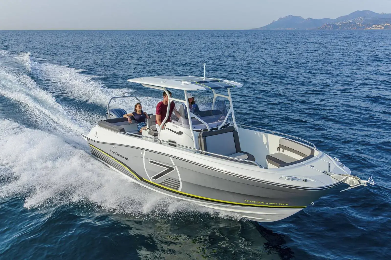 Jeanneau Cap Camarat 7.5 CC: centre-console sports boat under way at speed with T-top, passengers aboard and coastline behind