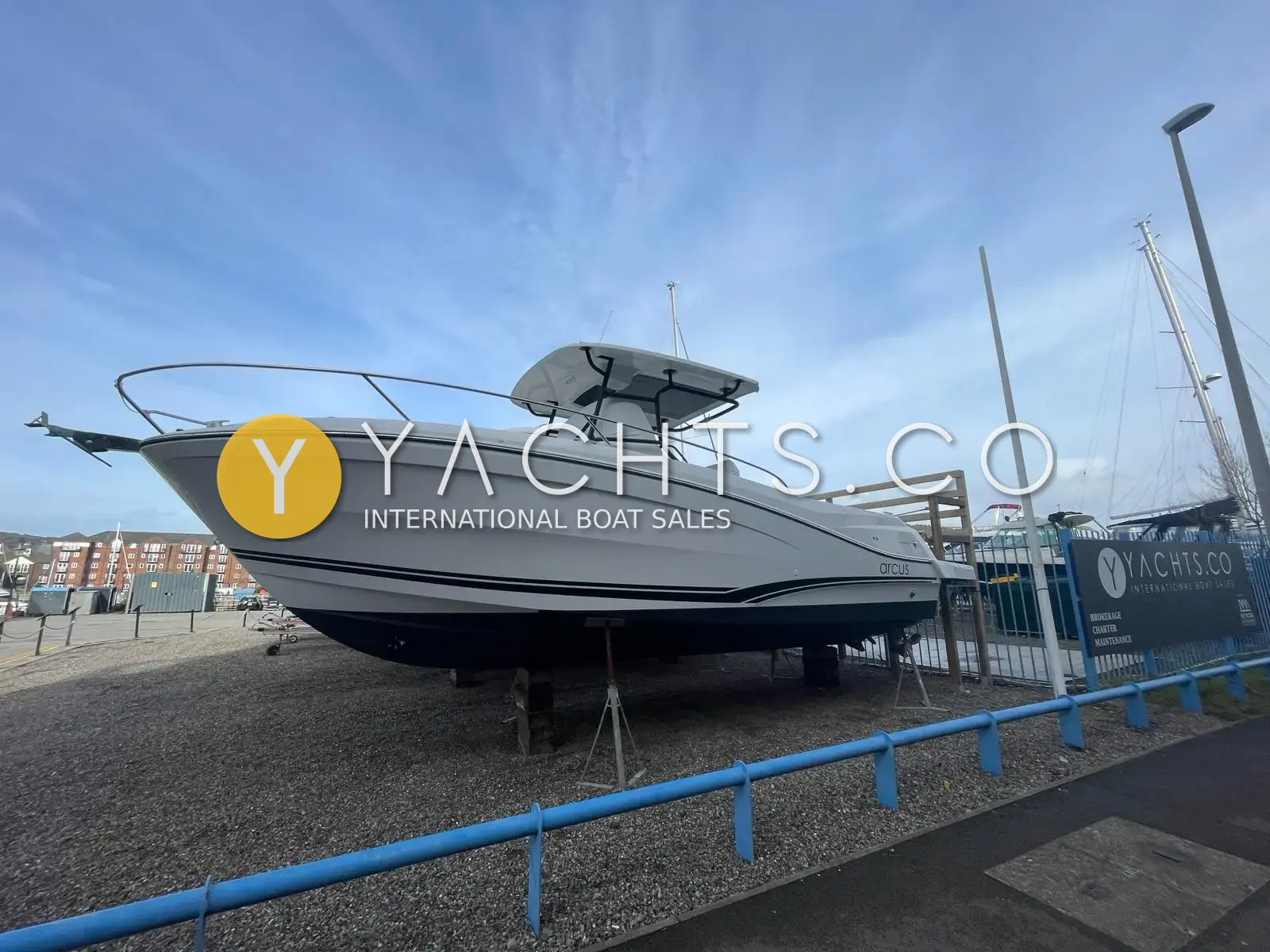 Jeanneau Cap Camarat 9.0 CC: starboard bow view of the white hull with navy stripes, ashore on stands in a Swansea boatyard