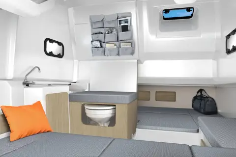 Jeanneau Cap Camarat 9.0 CC Serie 2: rendered cabin interior showing enclosed toilet, berth cushions, storage pockets and portholes