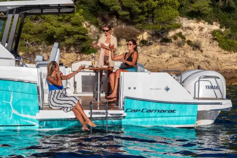 Jeanneau Cap Camarat 9.0 CC Series 2: side swim terrace lowered with guests seated by turquoise hull and twin white outboards