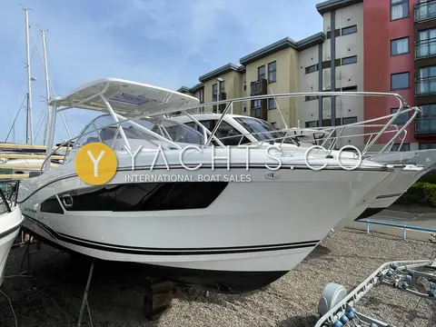 Jeanneau Cap Camarat 9.0 WA: starboard bow view of the white hull with dark hull windows, ashore in the marina