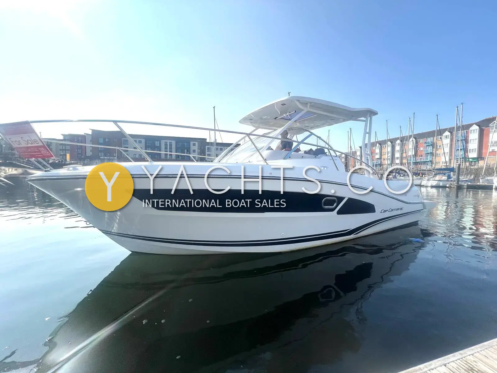 Jeanneau Cap Camarat 9.0 WA: starboard bow view of the white hull and T-top, moored in a marina beside flats