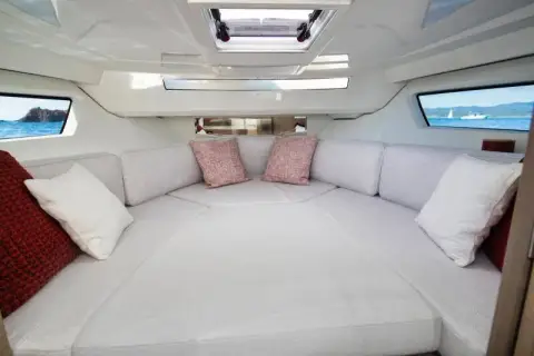 Jeanneau Cap Camarat 9.0 WA: forward cabin with wide V-berth in white upholstery, overhead hatch and hull windows