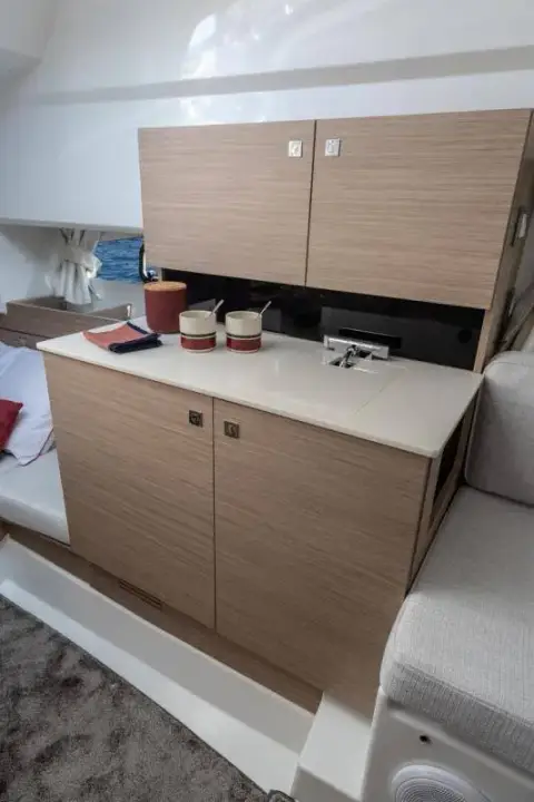 Jeanneau Cap Camarat 9.0 WA: interior galley unit in light wood finish with sink, pale worktop and wall cupboards