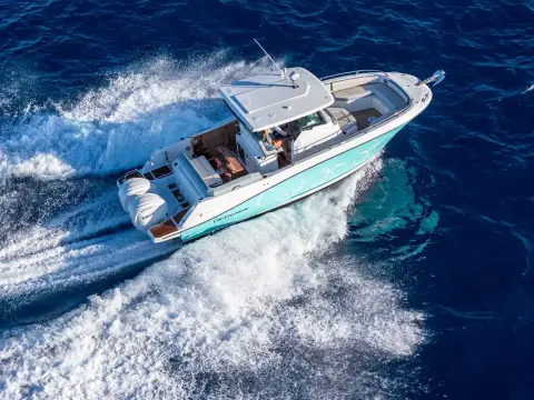 Jeanneau Cap Camarat 9.0 CC: aerial view at speed showing teal hull, hard top, cockpit layout and twin white outboards